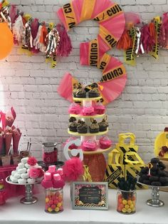 a table topped with lots of cupcakes and desserts next to a brick wall