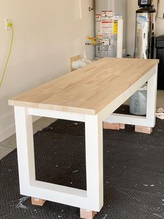 a wooden table sitting on top of a hard wood floor next to a white wall