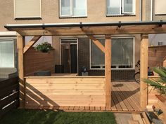 a wooden deck with a bench and potted plant in the back ground area next to a brick building