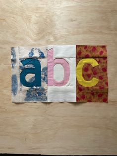 the letters are made out of fabric on top of a wooden surface with different colors