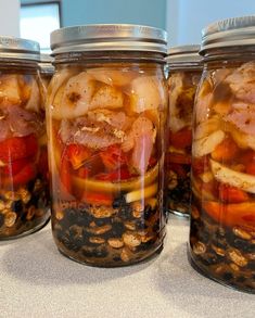 four jars filled with food sitting on top of a table