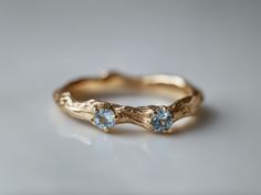 a gold ring with two blue stones on it's side, sitting on a white surface