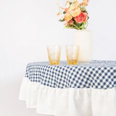 two glasses sitting on top of a table next to a vase with flowers in it