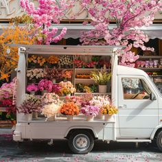 a white truck parked in front of a flower shop filled with lots of pink flowers