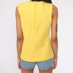 "Vintage 70s tank top in yellow. Sleeveless with a round neckline. Rear zipper. Note: The colour is blowing out a bit, it's not as bright in person. Every garment we sell is authentic vintage and one-of-a-kind! You will receive the exact item photographed. Condition: Very good vintage. Best fits women's: Small Material: Polyester MEASUREMENTS Taken from seam to seam while the garment is lying flat. Double the armpit, waist, and hips For reference, model is 5'10\" and measures 32-23-34. Length fr Retro Tank Vest Top, Retro Tank Top Vest, Retro Sleeveless Vest Top, Retro Spring Tank Top, Retro Spring Vest Tank Top, Retro Fitted Sleeveless Tops, Retro Vest Tank Top For Spring, Fitted Sleeveless Retro Tops, Retro Tank Tops For Spring