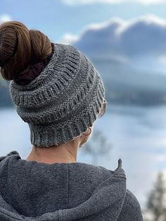 a woman wearing a knitted hat looking out over a lake