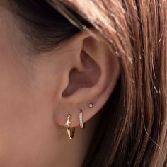 a woman's ear with two small diamond hoops