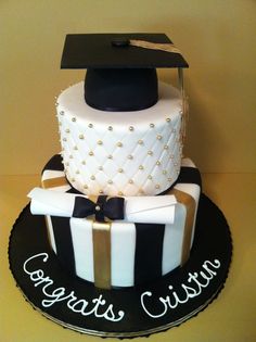 a graduation cake that is decorated with black and white stripes, gold trimmings and a mortar on top