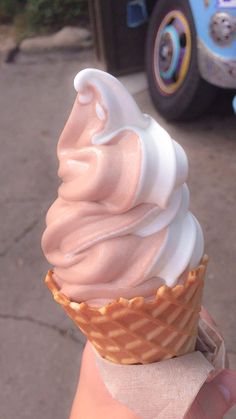 an ice cream sundae is being held up by someone's hand on the sidewalk