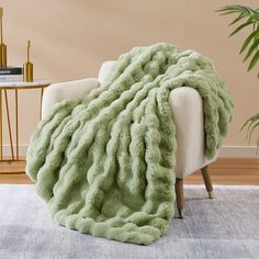 a chair with a green blanket on top of it next to a potted plant