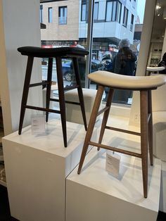 two stools sitting on display in front of a window