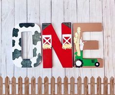 the word farm spelled out in wood letters on a white wooden fence with a toy tractor