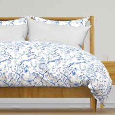 a bed with white and blue comforters on it