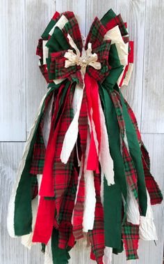 a red, white and green christmas wreath hanging on a wooden wall