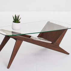 a glass table with wooden legs and a potted plant sitting on top of it