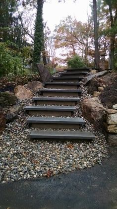 a set of steps leading up to the top of a hill surrounded by rocks and trees