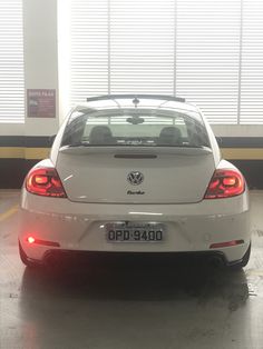 the back end of a white car parked in a garage