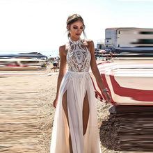 a woman is standing on the beach wearing a dress with high slits and an open back