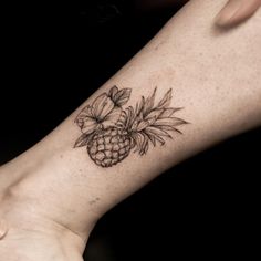 a pineapple tattoo on the ankle with flowers and leaves around it's center