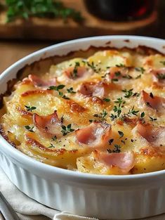 a casserole dish with ham and cheese in it on a table next to silverware