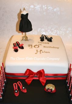 a birthday cake decorated with red ribbon and shoes