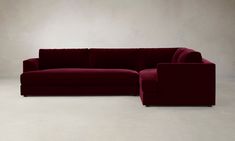 a large red couch sitting on top of a white floor next to a wooden chair