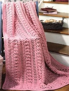 a pink crocheted blanket sitting on top of a stair case