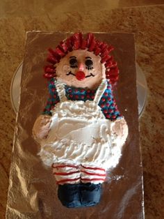 there is a cake that looks like a clown on the table with plastic wrapper