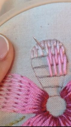 a close up of a person's hand holding a needle and thread