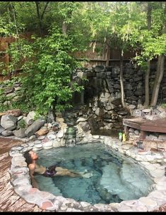 a man is swimming in a pool surrounded by rocks