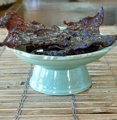 a bowl filled with meat sitting on top of a wooden table