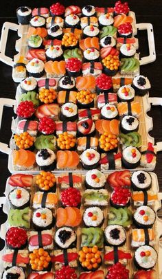 two trays filled with different types of sushi on top of each other,