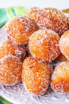 powdered sugar coated donuts on a white plate with green and yellow napkins