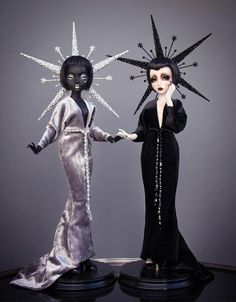 two dolls dressed in black and silver are standing next to each other