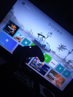 a person holding a remote control in front of a flat screen tv with games on it