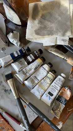 an assortment of paint and brushes sitting on top of a table