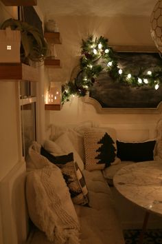 a living room filled with lots of furniture and christmas lights on the wall above it