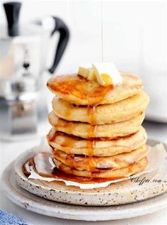 a stack of pancakes on a plate with syrup being drizzled over them