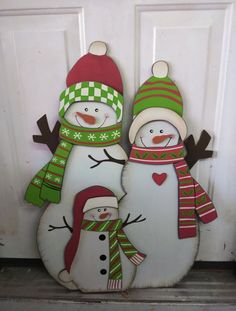 two snowmen standing next to each other in front of a door