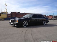 a black station wagon parked in a parking lot next to a large building and blue sky