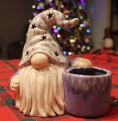 a ceramic figurine sitting on top of a table next to a christmas tree