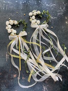 white flowers and ribbons are laid out on the ground with ribbon tied around them to make it look like they have fallen apart