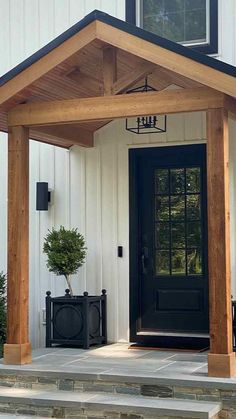 a black front door on a white house with a wooden porch and entry way leading to it