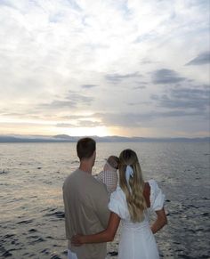 a man and woman standing on the edge of a boat looking out at the water