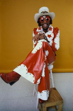 a man in a red and white suit sitting on a stool