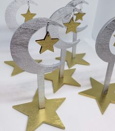 five silver and gold stars are hanging from the top of three metal moon and star earrings