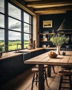 an open kitchen with wooden floors and black walls, along with large windows that look out onto the countryside