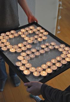 a person holding a tray with candles in the shape of a heart