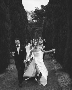 black and white photo of bride and groom walking through the garden with their arms in the air