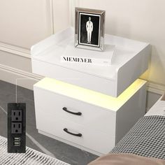 a white night stand with two drawers and a photo frame on top that says memeer